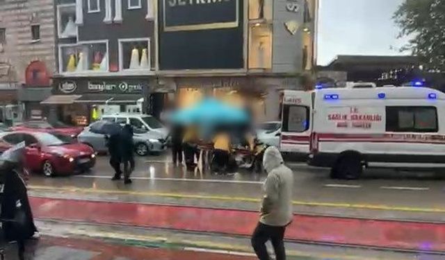 Otomobilin çarptığı yaralıyı yağmurdan korumak için şemsiye tuttular